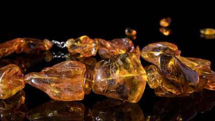 Luxurious sparkling orange amber necklace close up on a black background with reflection.  Amber texture, crystal healing, talisman. 