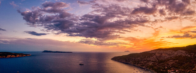 Aerial panoramic drone shot of burning sky sunset clouds on Adriatic horizon from Komiza on Vis Island in Croatia summer