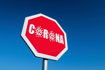 Stop traffic sign with CORONA text where O is replaced by an illustration of a coronavirus. Express the wish to stop COVID-19 illness