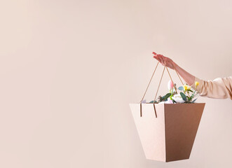 Cropped image of a hand with a craft paper bag with flowers.