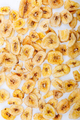 Banana chips, dehydrated slices of fresh ripe bananas as food background. Dried bananas.