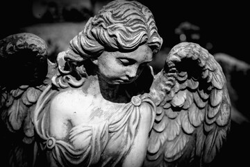 Dramatic photo of sad angel with deep shadows. Fragment of ancient statue. Death and pain concept. Horizontal image.