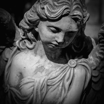 Dramatic image of sad angel with deep shadows. Fragment of ancient statue. Death and pain concept
