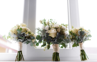 Close up view of three delicate bouquets in green and white color standing on the window sill.