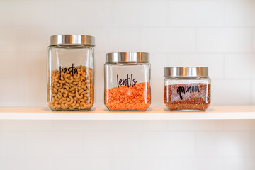 Glass canisters lined up in a row on a kitchen shelf