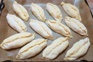 raw small pies on a baking sheet for food background