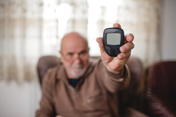 Senior men with glucometer checking blood sugar level at home