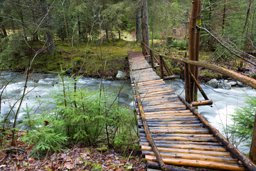 Beautiful wooden pedestrian bridge over a fast mountain river © anatoliil
