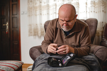 Senior men with glucometer checking blood sugar level at home