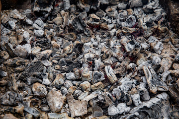Glowing embers in hot red color, abstract background. The hot embers of burning wood log fire. Firewood burning on grill. Texture fire bonfire embers.