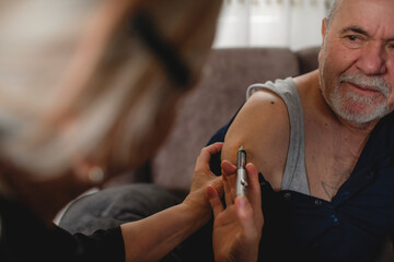 Senior woman giving insulin her diabetic husband at home