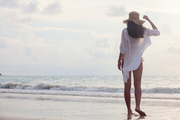 young woman in straw hat enjoying evening by the beach