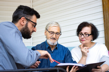 Bank agent planning with retired senior couple their future investment opportunities. Financial advisor offer tariff plan,interest rates,insurance conditions to elderly man and woman.Retirement plan