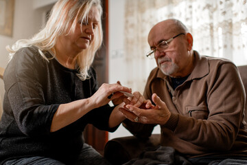 Senior woman checking blood sugar of her diabetic husband at home
