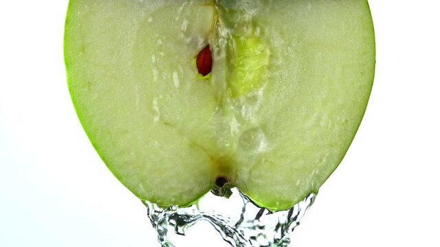 Super Slow Motion Detail Shot of Flowing Water from Apple Slice on White Background at 1000fps.