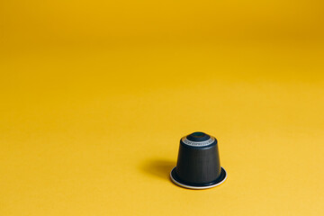Fototapeta na wymiar One coffee capsule isolated on yellow background