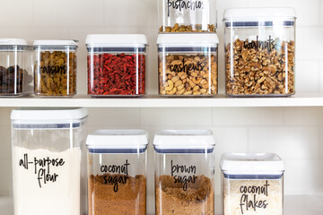 Baking ingredients in BPA-free plastic storage containers with labels in an organized kitchen pantry