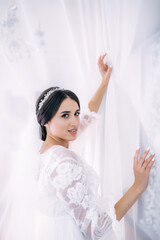 Gorgeous bride in an elegant dress, in a hotel room, morning before wedding preparations.