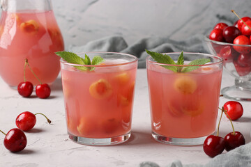Kissel with sweet cherries in two glasses and jug on gray background, Horizontal format