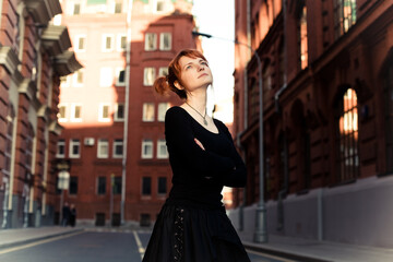 girl in black clothes standing in the middle of the road folded her hands on her chest looking up