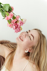 Obraz na płótnie Canvas white young blonde woman sniffs a bouquet of pink flowers and smiles on a white background