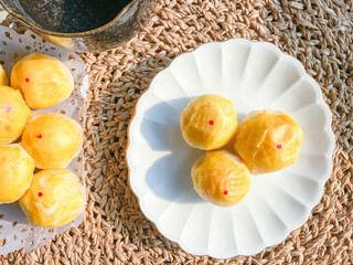 Close up moon cake traditional Chinese cake pastry with salted egg lava on white dish plate on Woven rattan background. Famous sweet dessert in Asia ancient party or local festival.