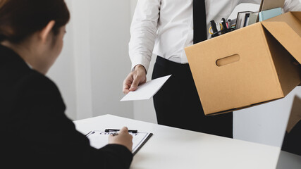 Employee handed over a document envelope and a box of work equipment beside him, Businessman submits resignation documents to their supervisor and take personal equipment in a brown box.
