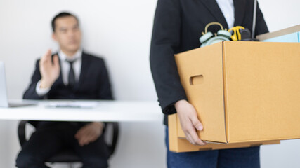 Young woman wearing a black suit raises a brown cardboard box from the office, Businessmen pack...
