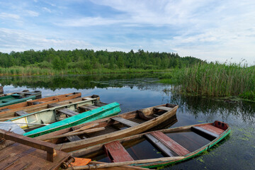 Naklejka na ściany i meble Old wooden boats near the river pier on a warm summer day.