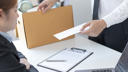 Employee handed over a document envelope and a box of work equipment beside him, Businessman submits resignation documents to their supervisor and take personal equipment in a brown box.