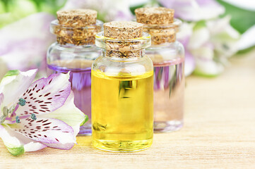 Obraz na płótnie Canvas Glass bottles aroma oil and flowers on wooden table. Spa Treatment