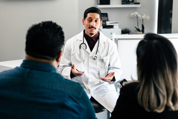 Hispanic family doctor consulting with patients in doctors office