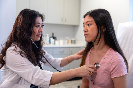 Asian doctor checks patient heartbeat using stethoscope