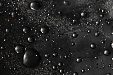 Surface tension. Water drops on the surface covered with foil.