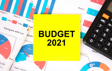 Yellow sticker with text Budget 2021 with calculator white pen on the diagrams
