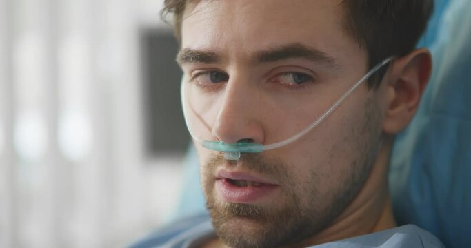 Upset man lying with oxygen nasal catheter on face preparing for surgery