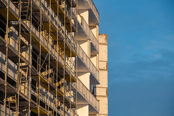 Fototapeta premium Metal-wood scaffolding on the facade of an apartment building against the sky outside