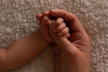 parents hands holding their baby's hand