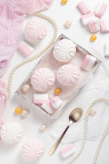 Pink zephyr and marshmallow in box on a white rustic wooden table. Top view, flat lay