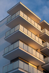 The building is a new block of flats, two-storeyed with glass balconies from the outside against the sunset sky