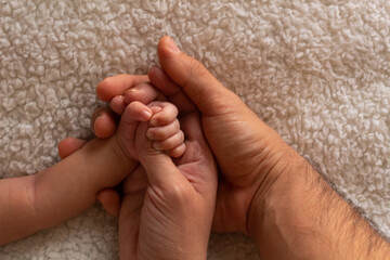 parents hands holding their baby's hand