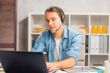 Workplace of freelance worker or sudent at home office. Young man works using computer and other devices. Remote job.