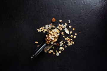 spooned muesli on a black table, healthy food concept and copy space