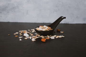 spooned muesli on a black table, healthy food concept and copy space