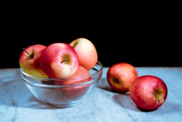 Bodegón de siete manzanas rojas sobre fondo oscuro. 