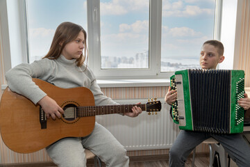a boy and a girl will play a duet on the guitar and button accordion while studying at a music...