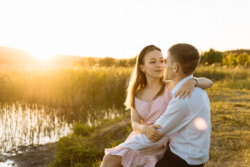 a young couple in love at sunset near the lake. a date in the park of a couple in love. the concept of romance and love.