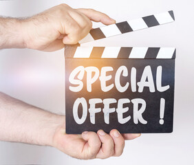 Obraz premium On a white background, a man holds a clapperboard in his hands on which it is written - SPECIAL OFFER