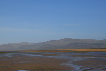 the smooth wet sand at the end of an estuary with the mountains in the background