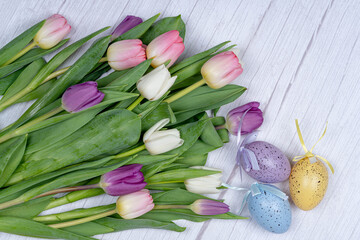 Easter eggs, a bouquet of tulips from above on a gray background. Happy holiday concept ER